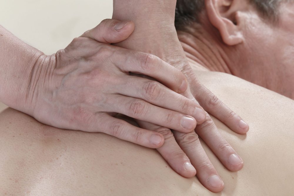 Hands massaging man's back.